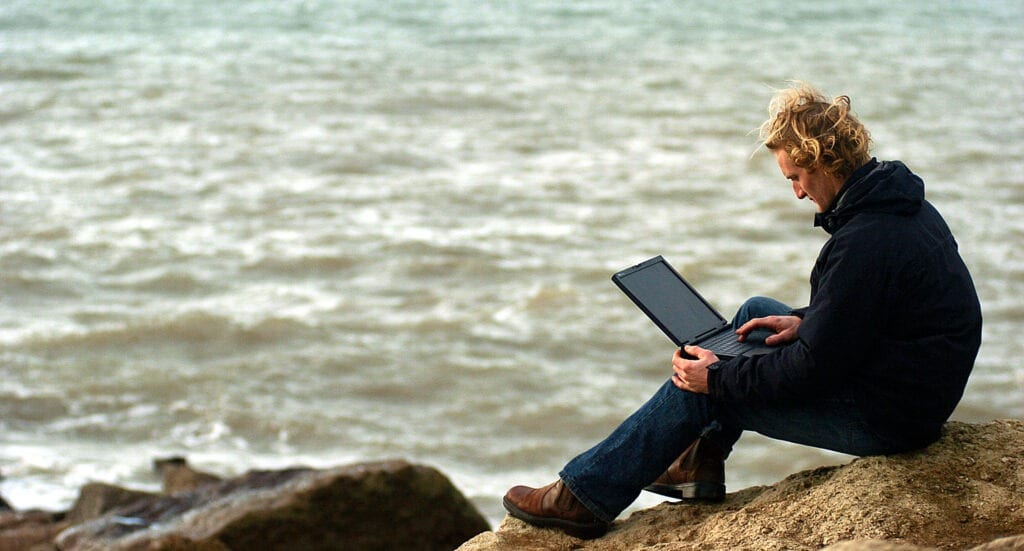 man working away from office sea laptop England