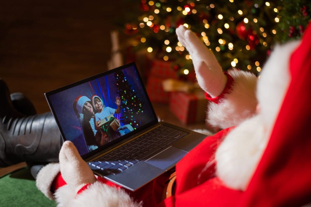 Happy mom and son talking to santa claus by video chat on a laptop. Woman and boy remotely wishes Merry Christmas